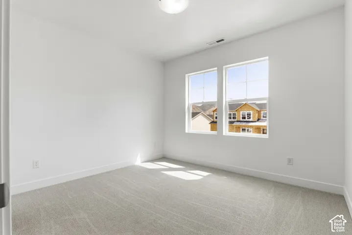 Neutral-toned carpet flooring, white painted walls, and two large windows