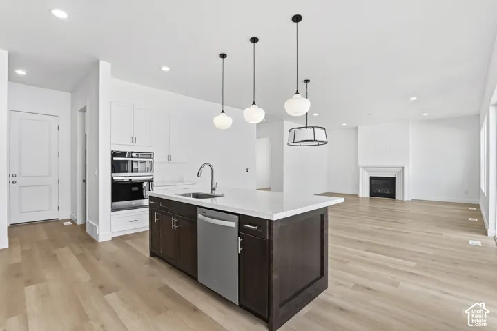 Kitchen island with an undermount sink, stainless steel dishwasher, and pendant lighting