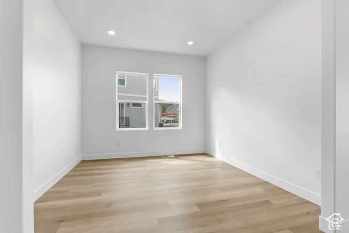Recessed lighting, wood-finish flooring, and white walls throughout