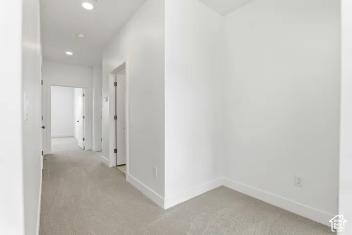 Recessed ceiling lighting illuminates a carpeted hallway with multiple doorways