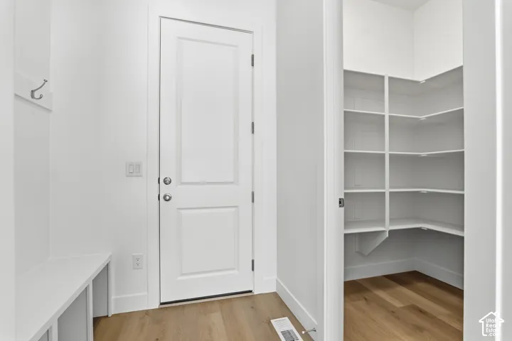 White interior door, built-in storage bench, and wood-finish flooring
