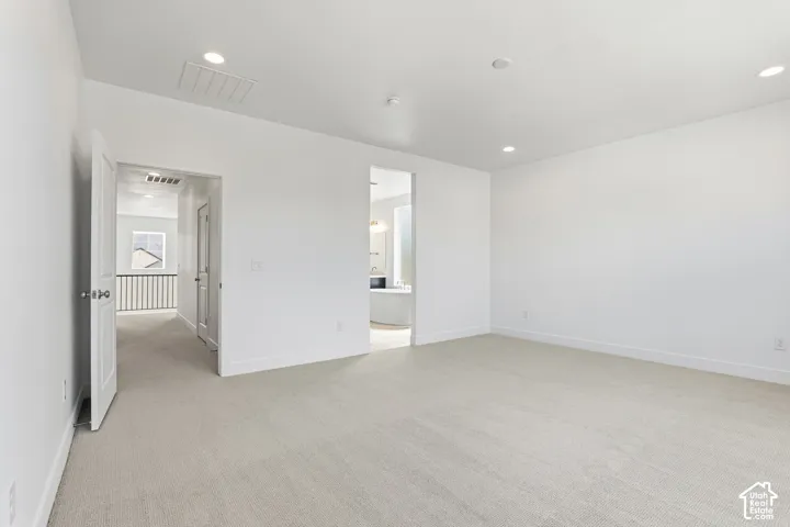 Recessed lighting, light-toned carpeting, and white walls