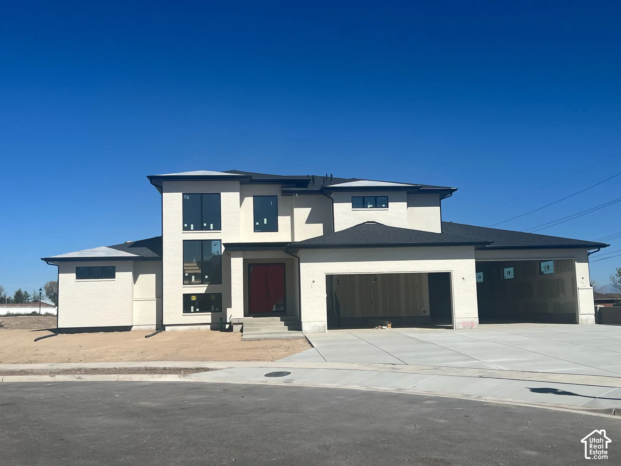 Contemporary stucco exterior with a multi-level design, dark-shingle roofing, expansive window placements, and a concrete driveway