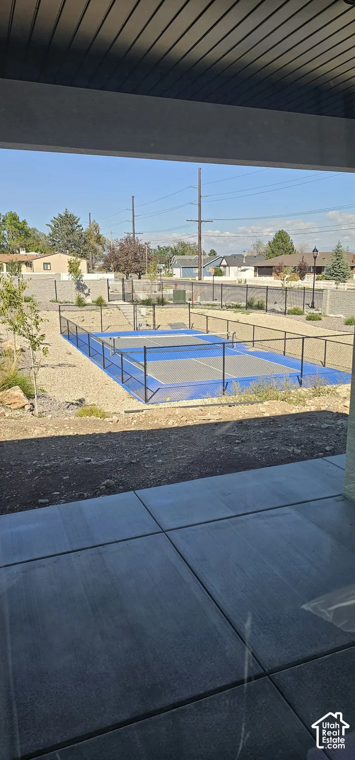 Outdoor sport court with blue surfacing, surrounded by black fencing
