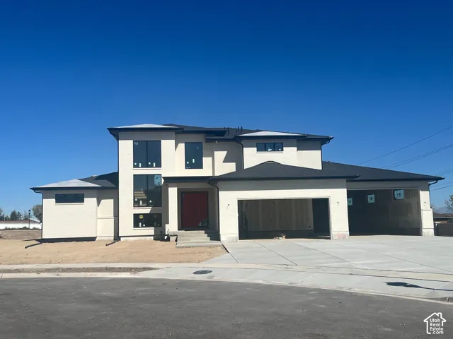 Contemporary stucco exterior with a multi-level design, dark-shingle roofing, expansive window placements, and a concrete driveway