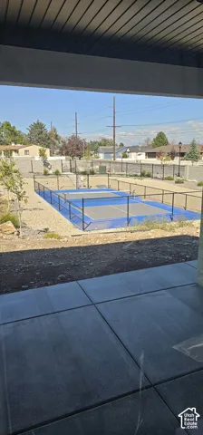 Outdoor sport court with blue surfacing, surrounded by black fencing
