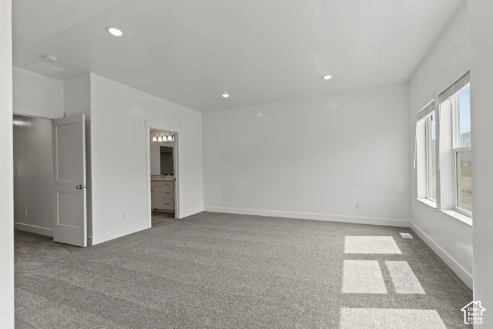 Spacious room with plush gray carpeting, recessed ceiling lighting, and multiple windows