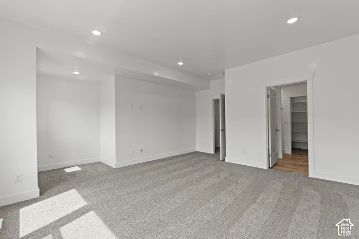 Recessed lighting, light gray carpeting, crisp white walls, white trim, and a built-in closet system