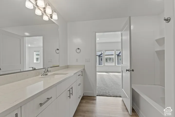 Dual vanity with integrated sinks, light-toned countertop, wood-finish flooring, and white paneled cabinetry