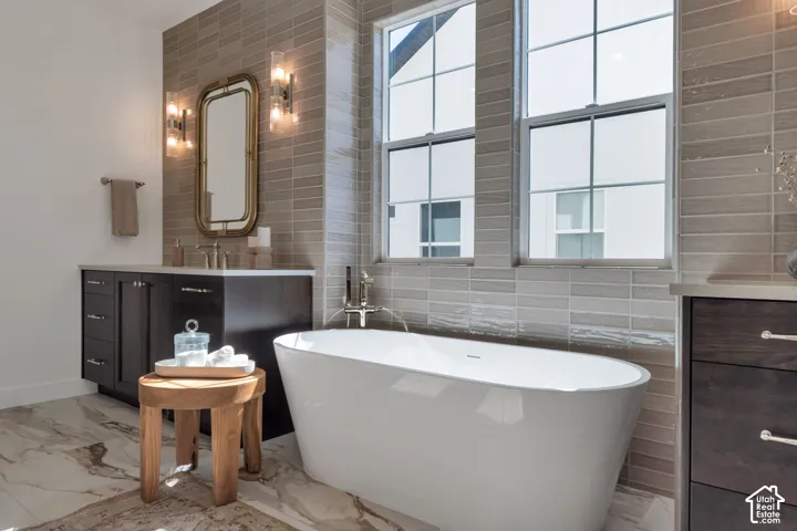 Freestanding bathtub with floor-mounted faucet, dual windows, and tile surround