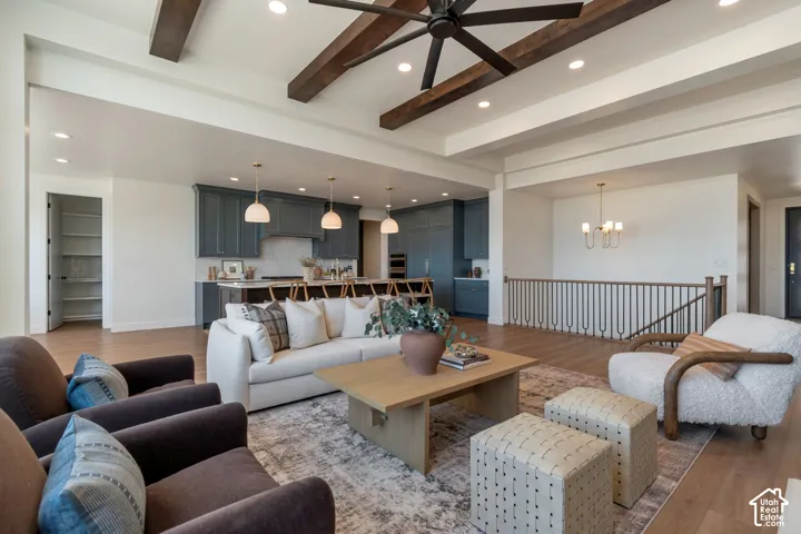 Exposed wood beams, wood-finish flooring, recessed lighting, built-in shelving, and a decorative staircase railing