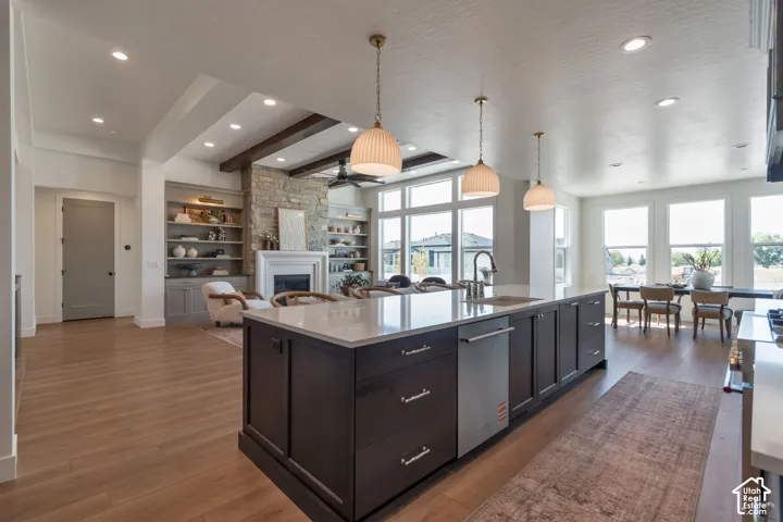 Open-concept living area featuring a kitchen island with built-in sink, wood-finish flooring, recessed lighting, and large windows