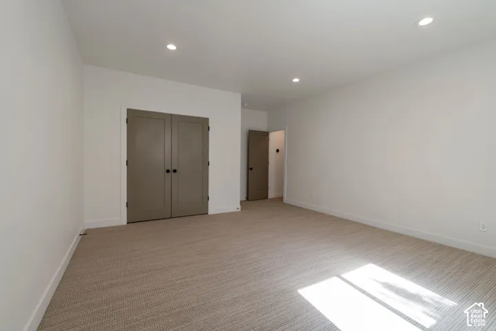 Recessed lighting illuminates the neutral-toned carpet and light-colored walls