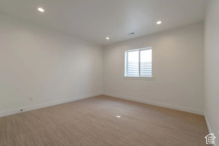 Recessed ceiling lighting, white painted walls, and light-toned carpet flooring