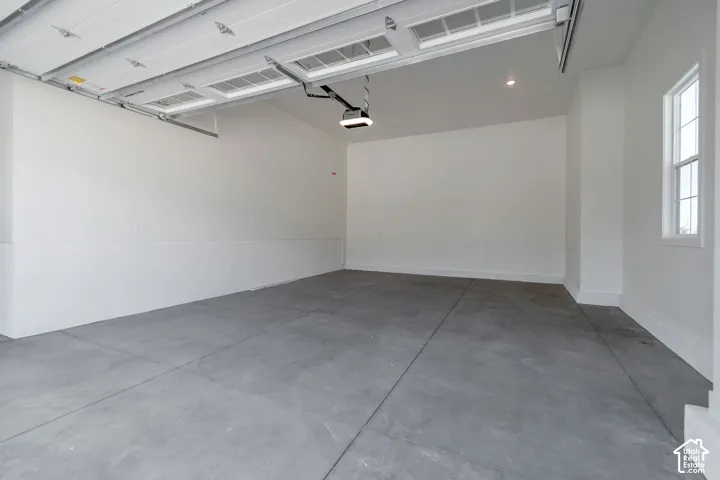 Garage featuring a sectional overhead door with window inserts, automatic opener, recessed lighting, and a single pane window with grid