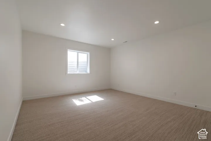 Recessed lighting, neutral paint, light-toned carpet flooring, and a single window