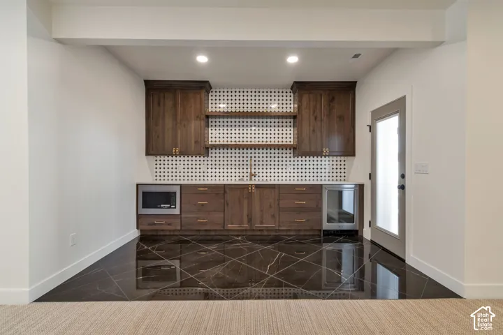 Built-in cabinetry with a beverage refrigerator, a microwave, and open shelving