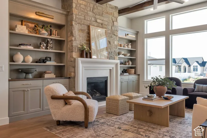 Stone-clad fireplace with a classic mantel, built-in shelving, wood-finish flooring, and expansive windows