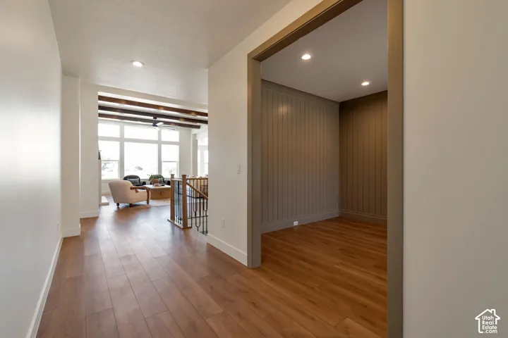 Wood-finish flooring throughout, recessed lighting, and a prominent staircase with dark wood and metal balusters