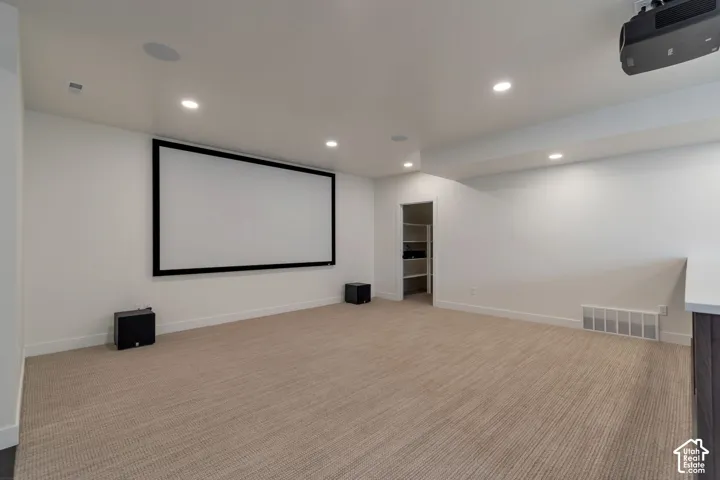 Recessed lighting, ceiling-mounted projector, wall-mounted screen, and neutral-toned carpeting