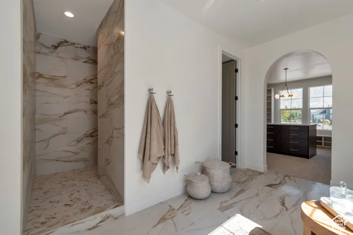 Walk-in shower with marble-look tile surround and recessed lighting