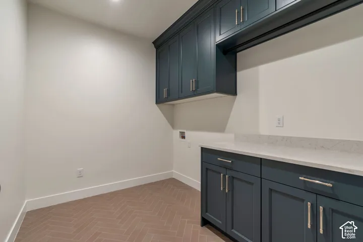 Built-in cabinetry with modern hardware, white countertops, and herringbone-patterned flooring