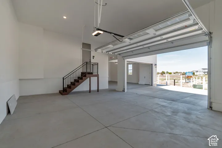 Expansive garage space with concrete flooring, recessed lighting, and an open garage door