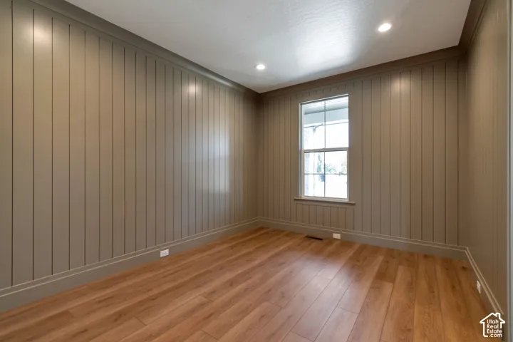 Wood-finish flooring, vertical paneling, recessed lighting, and a double-hung window