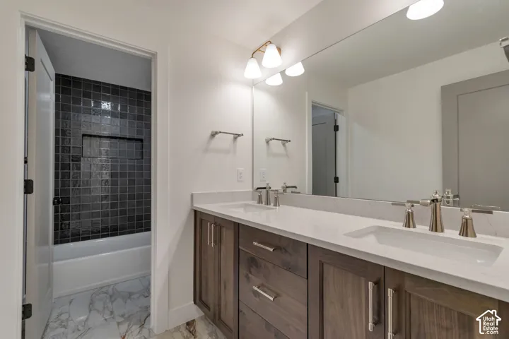 Dual vanity with integrated sinks, brushed nickel fixtures, wood-finish cabinetry, and a full-width mirror