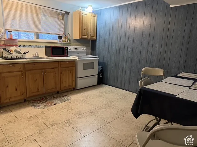 Kitchen featuring wood cabinetry, a white electric range, tiled flooring, and a patterned backsplash
