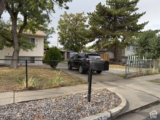 Property featuring a two-story residence with siding exterior, mature trees, and a chain-link fence