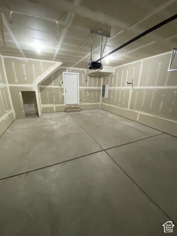 Concrete flooring, exposed ceiling beams, white interior door, wall-mounted electrical panel