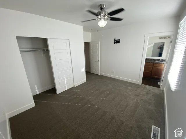Plush carpet flooring, ceiling fan with integrated lighting, white paneled closet doors, and a wall-mounted bracket