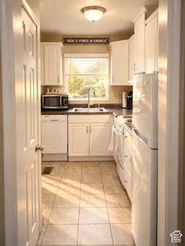 Kitchen featuring white cabinetry, stone-finish countertops, stainless steel sink, and tile flooring