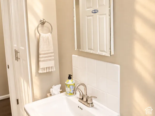 Pedestal sink with a brushed nickel faucet, ceramic tile backsplash, and a wall-mounted mirror