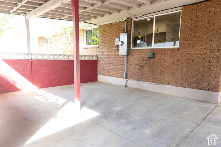 Covered concrete patio with a painted block wall and exposed brick exterior