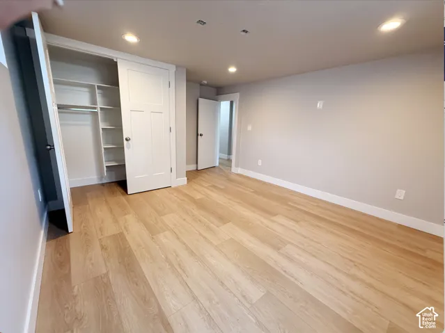 Wood-finish flooring, recessed lighting, white trim, and a built-in closet with shelving