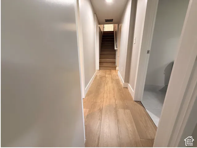 Hallway featuring wood-finish flooring, light-toned walls, and a recessed light fixture