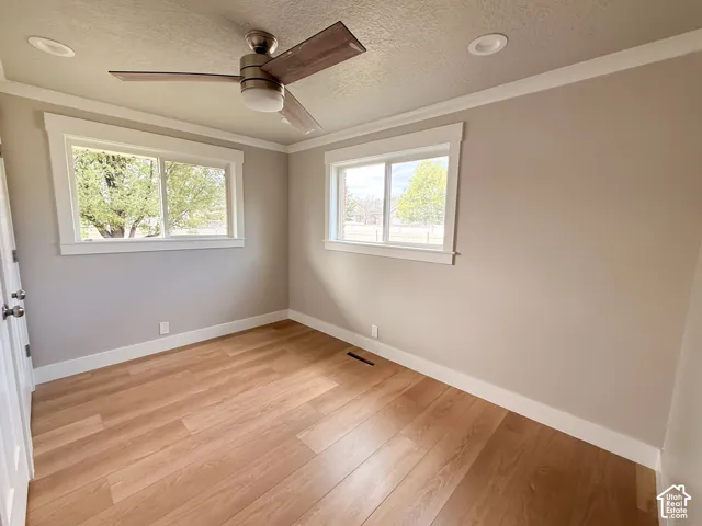 Wood-finish flooring, two large windows, white trim, ceiling fan with light, and recessed ceiling lighting
