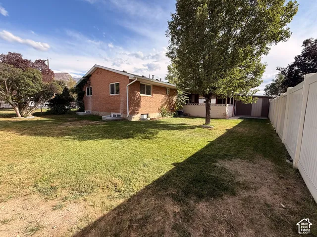 Expansive grassy yard featuring mature trees and a solid vinyl fence