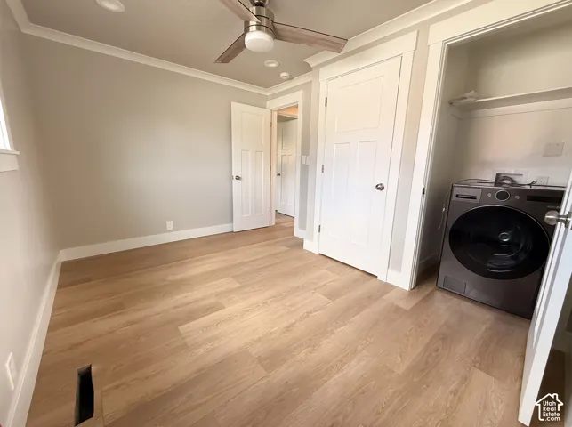 Wood-finish flooring throughout, ceiling fan with integrated lighting, recessed lighting, and a dedicated laundry area with a modern appliance