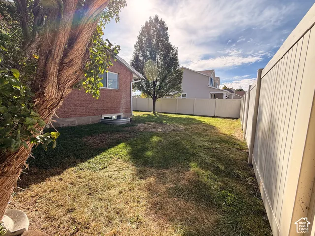 Brick exterior, mature tree, window well, vinyl fencing, manicured lawn