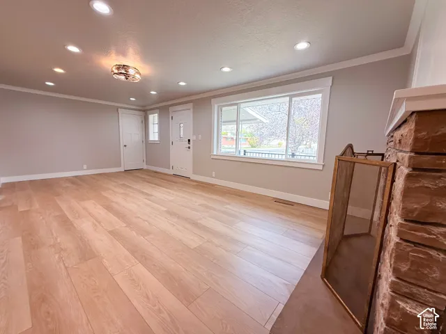 Wood-finish flooring throughout, recessed lighting, and a stone fireplace with a substantial hearth