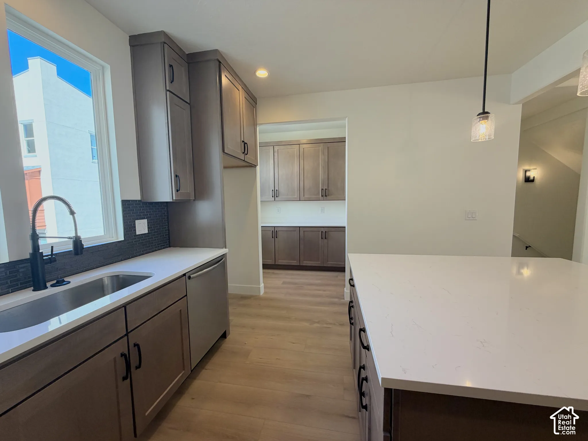 Kitchen featuring neutral cabinetry, a stainless steel sink, a modern pull-down faucet, a tile backsplash, and light-toned countertops