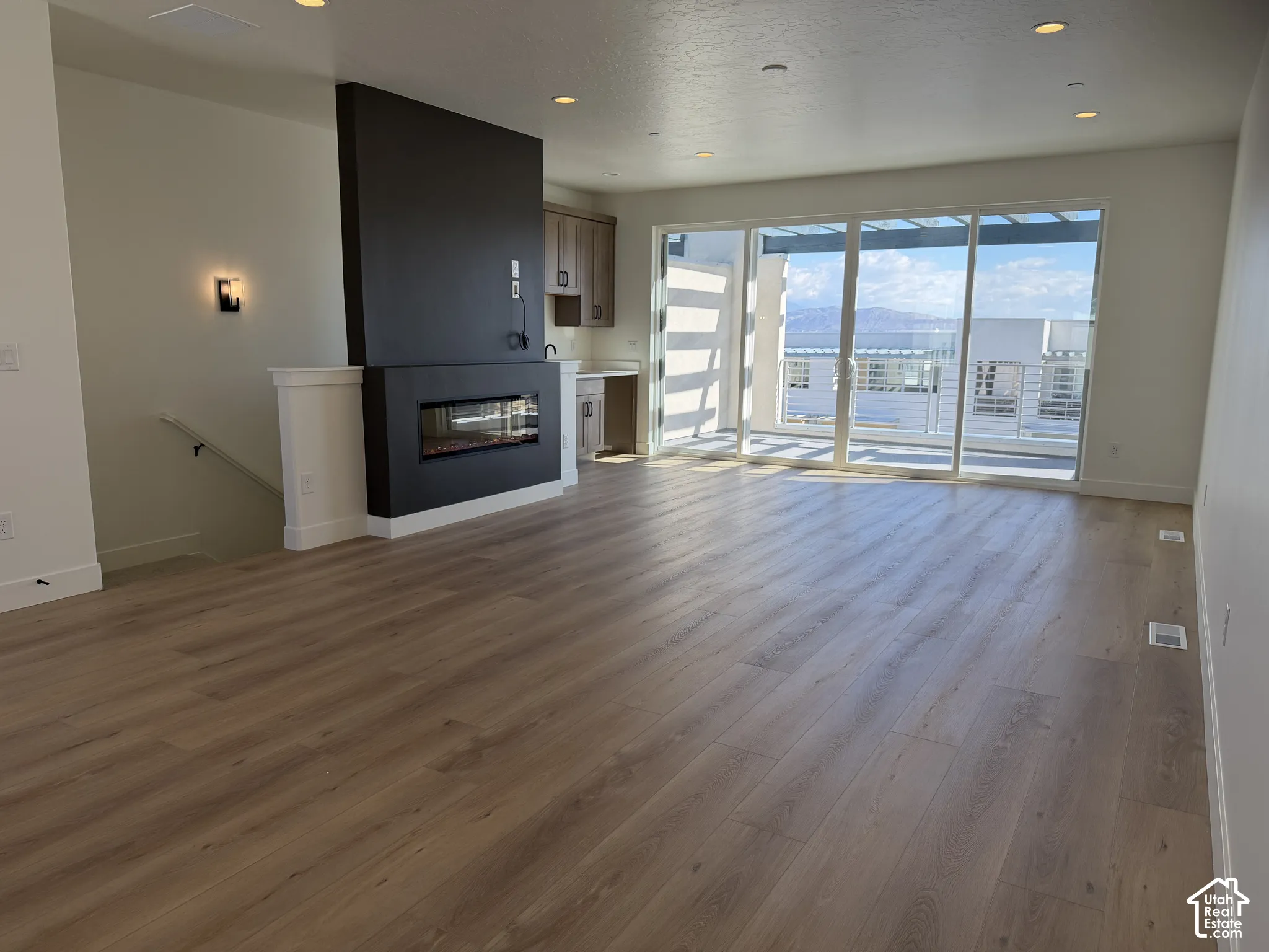 Wood-finish flooring, contemporary fireplace feature, built-in cabinetry, sliding glass doors, recessed lighting