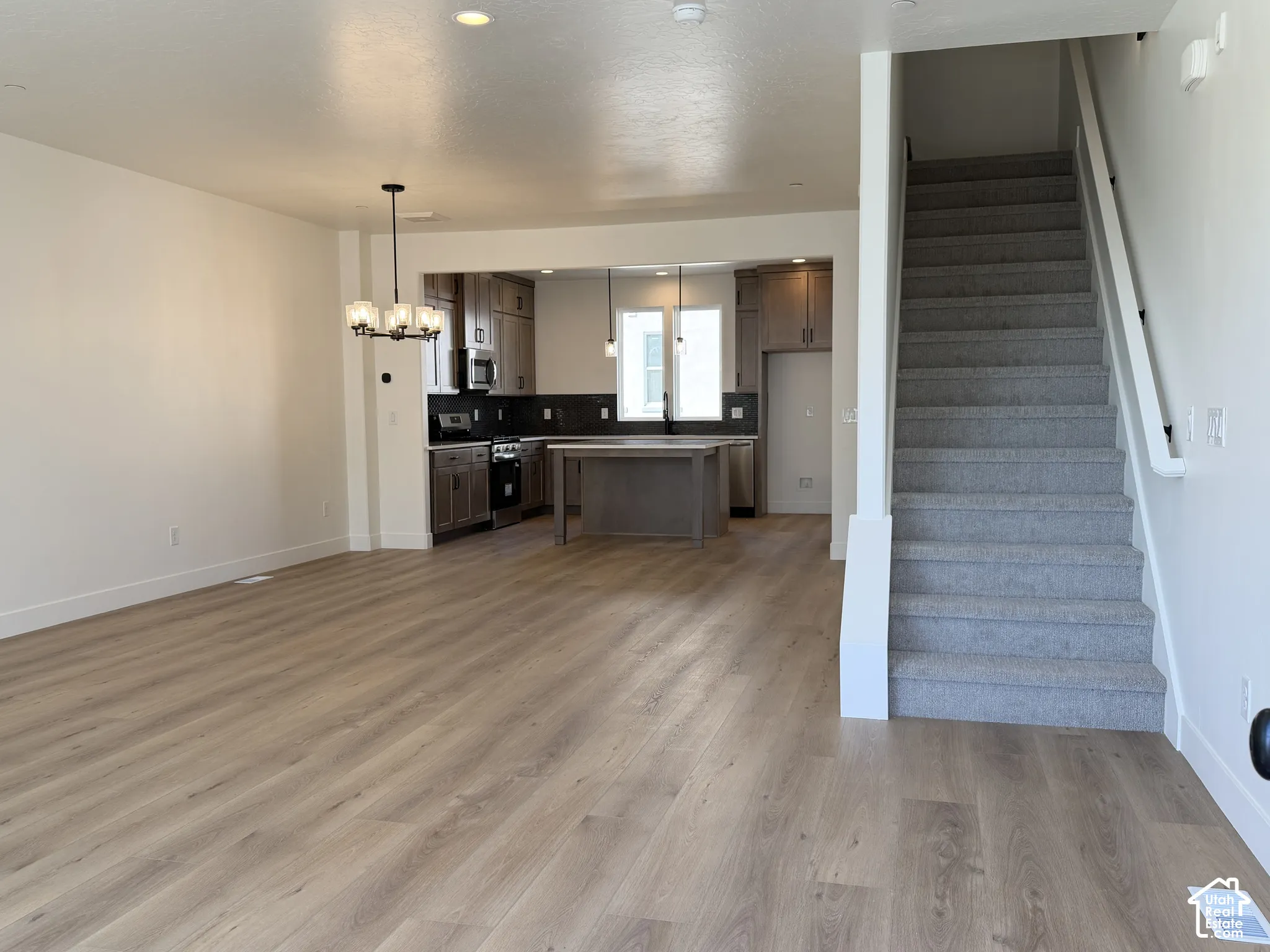 Open-concept living area featuring wood-finish flooring, recessed lighting, and a modern chandelier