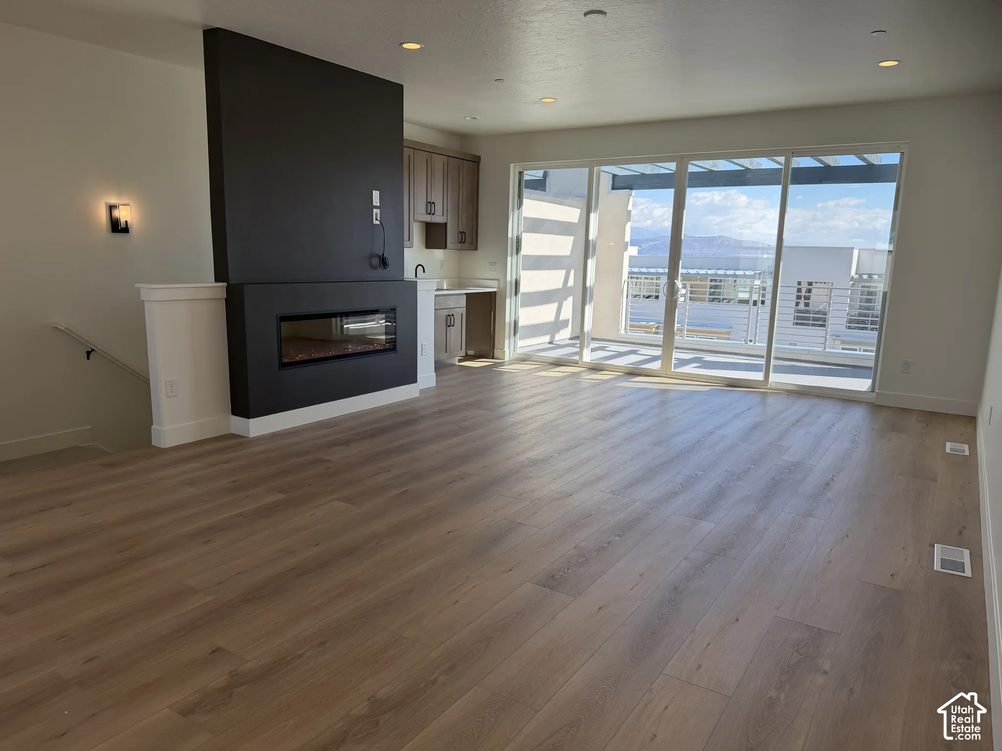 Open-concept living space with wood-finish flooring, a contemporary built-in fireplace, and expansive sliding glass doors