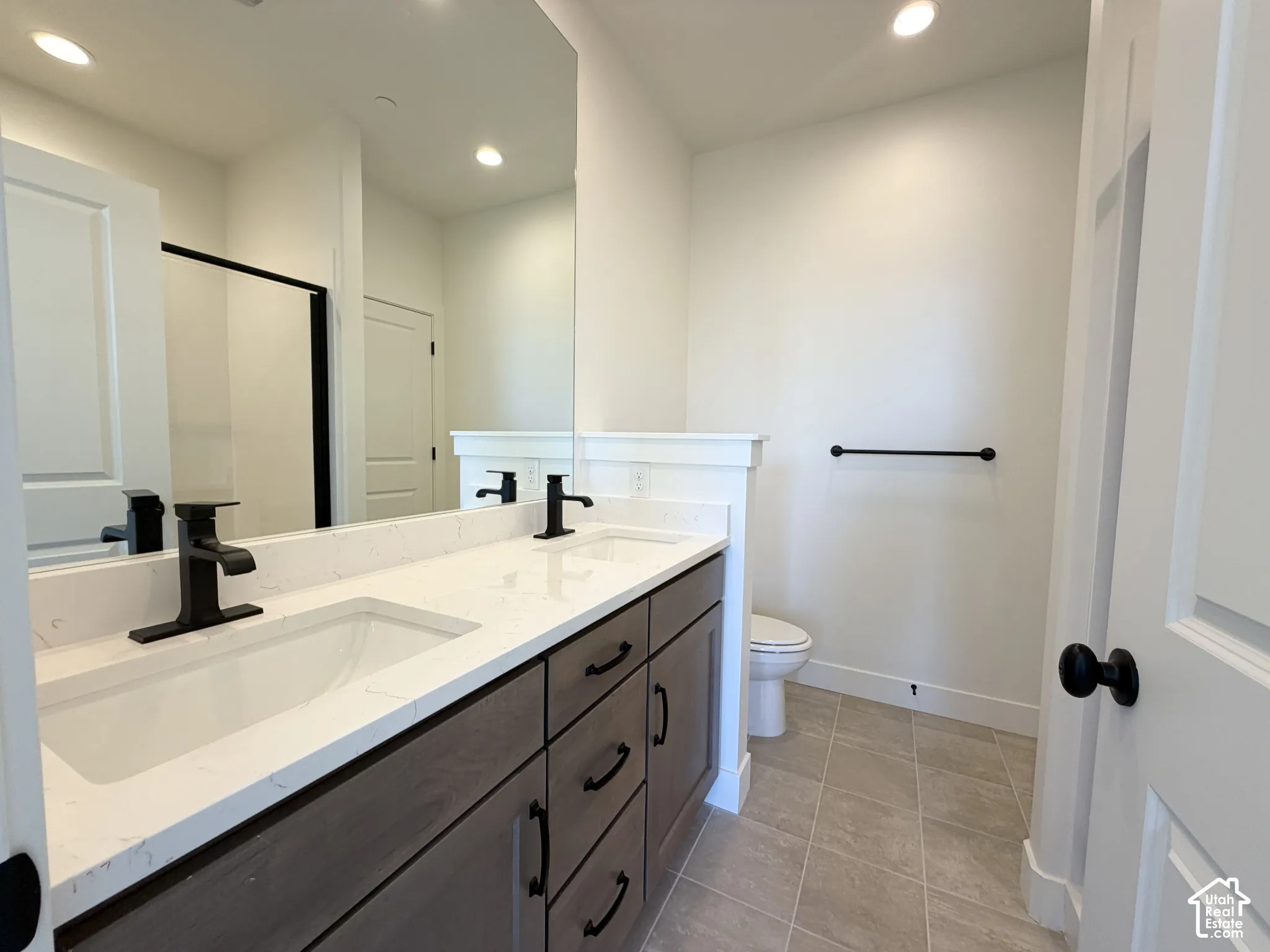 Double vanity with integrated sinks, white countertop, dark wood-finish cabinetry, and matte black fixtures