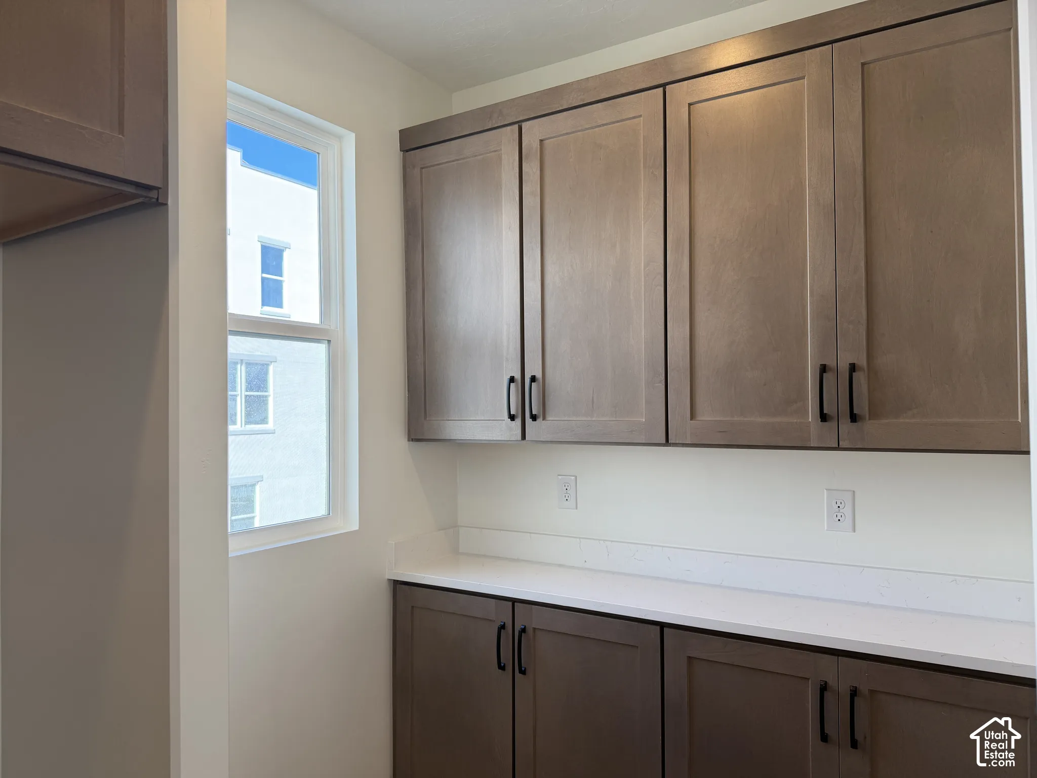 Built-in cabinetry with dark hardware, white countertop, and natural light from a single window
