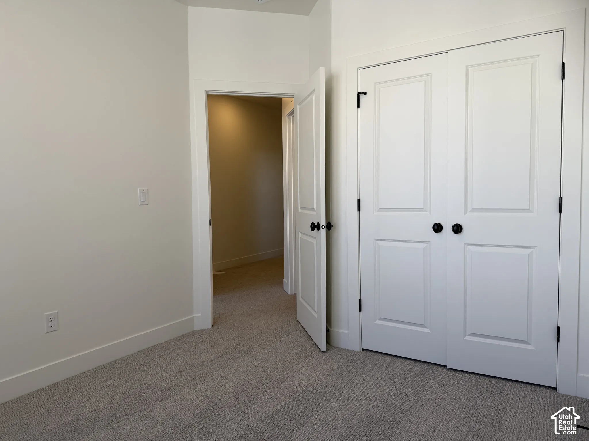 Plush carpeting, crisp white walls, and a white two-panel closet door with black hardware